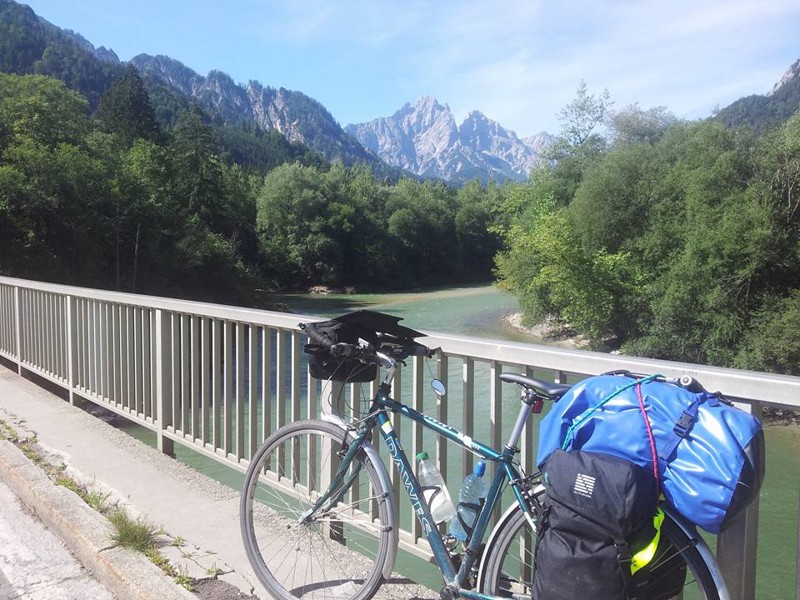 Bike with panniers on a bridge in the Alps with mountains in the background